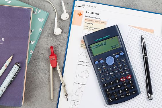 Tisch mit Mathebuch, Taschenrechner, Zirkel und Stiften