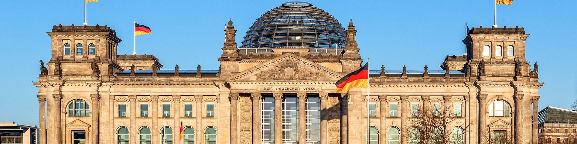 Das Reichstagsgebäude in Berlin mit Deutschland Fahnen vor dem Gebäude und auf dem Dach