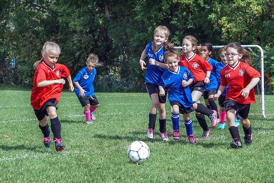 Mädchen in roten und blauen Trikots spielen Fußball