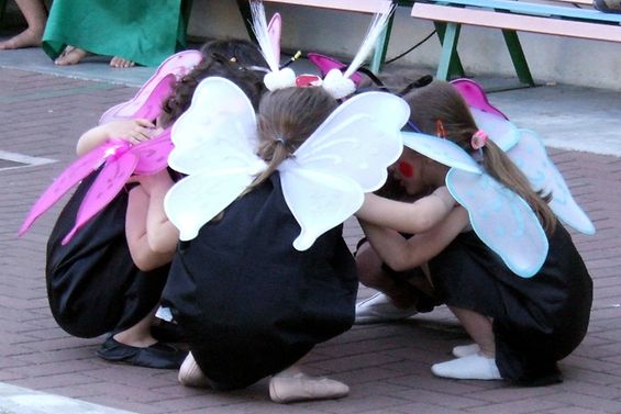 Kinder mit Schmetterlingsflügeln hocken im Kreis
