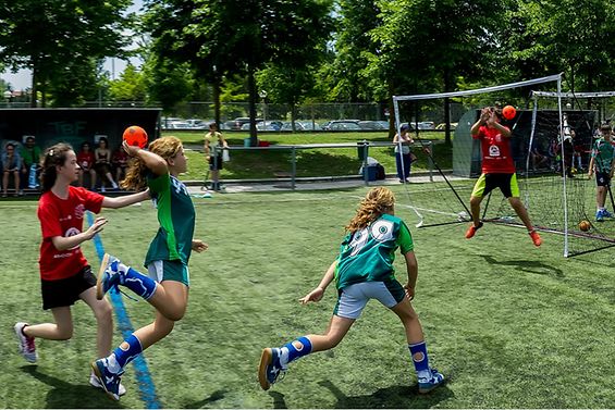 Kinder spielen Handball auf Rasenplatz