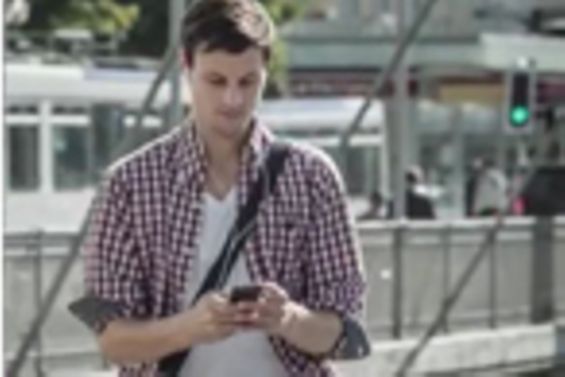 Jugendlicher bewegt sich auf das Smartphone schauend im Straßenverkehr